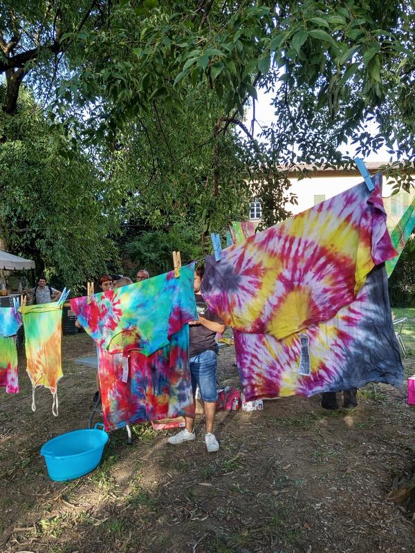 Teli tie-dye colorati stesi ad asciugare tra gli alberi