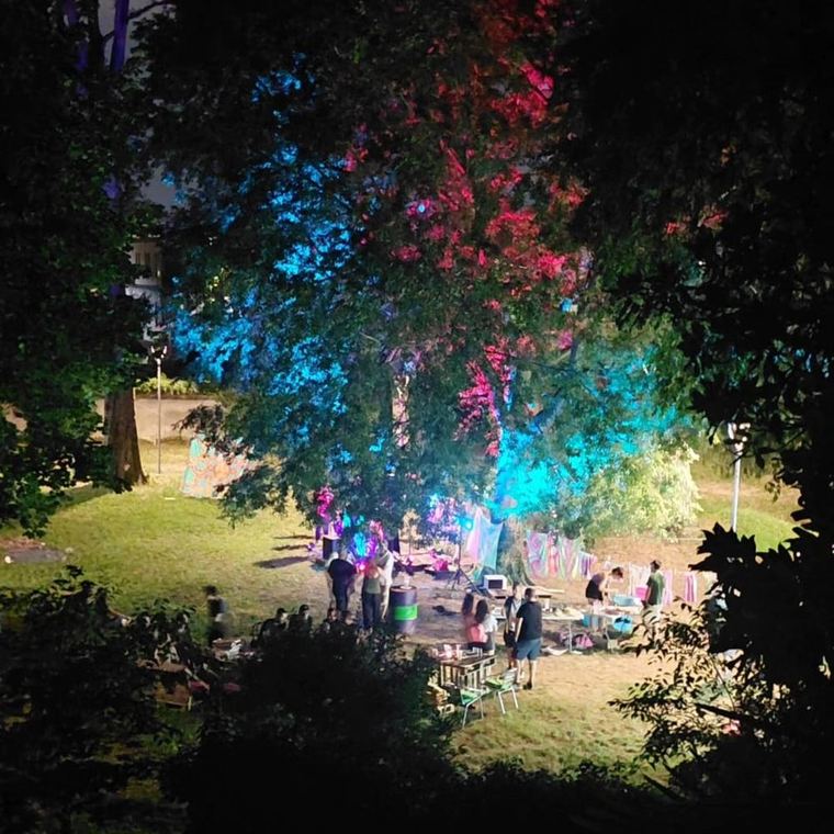 Il parco di notte illuminato di rosso e blu con la folla tra gli alberi